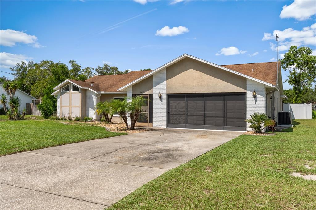 A single-story house with a white brick facade, brown roof, and a concrete driveway — 2285 GODFREY AVENUE, SPRING HILL, FL