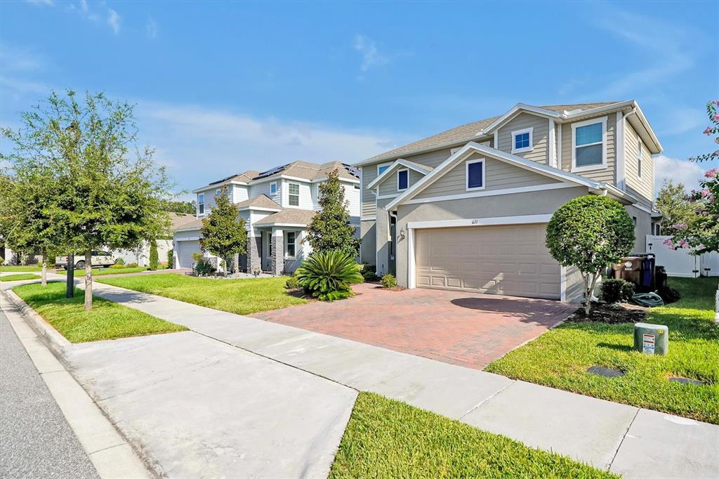 A two-story suburban house with a brick driveway, tan siding, and a two-car garage — 1121 HENDON LOOP, DAVENPORT, FL