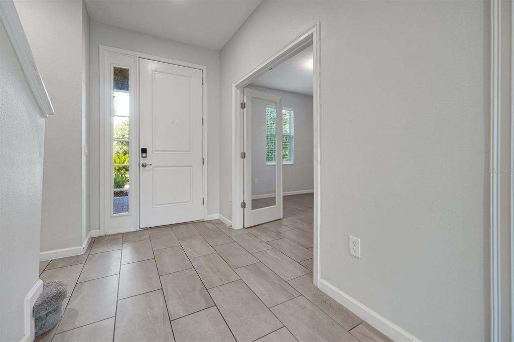 A bright entryway features light gray walls, tile flooring, a white front door, and French doors — 1121 HENDON LOOP, DAVENPORT, FL