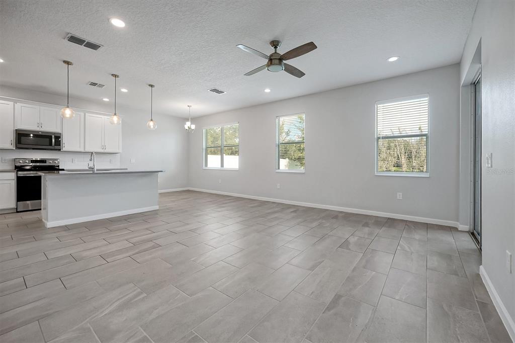 An open-concept kitchen and living area with gray tile flooring, white cabinets, and recessed lighting — 1121 HENDON LOOP, DAVENPORT, FL