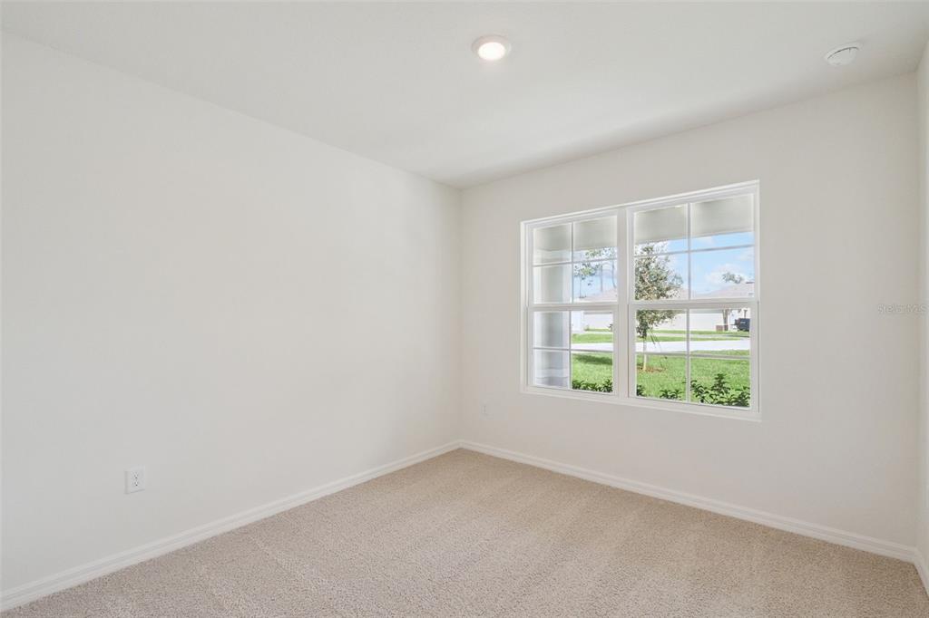An empty bedroom features beige carpet, white walls, and a window overlooking a suburban street — 847 SEAGROVE TRAIL, ST CLOUD, FL