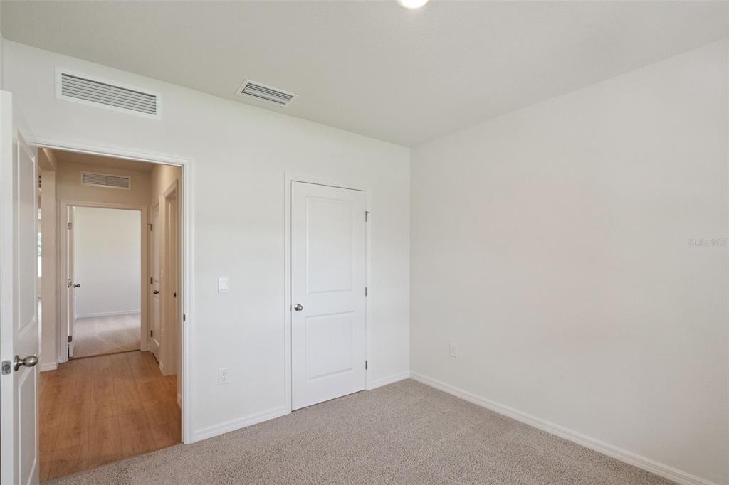 An empty bedroom features white walls, beige carpeting, and a closed white interior door — 847 SEAGROVE TRAIL, ST CLOUD, FL