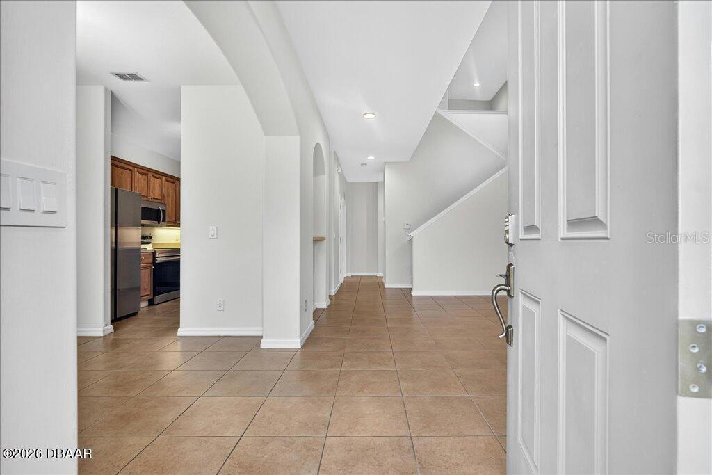 An entryway with tile flooring leads to a kitchen and a staircase — 3616 TRESTO STREET, NEW SMYRNA BEACH, FL