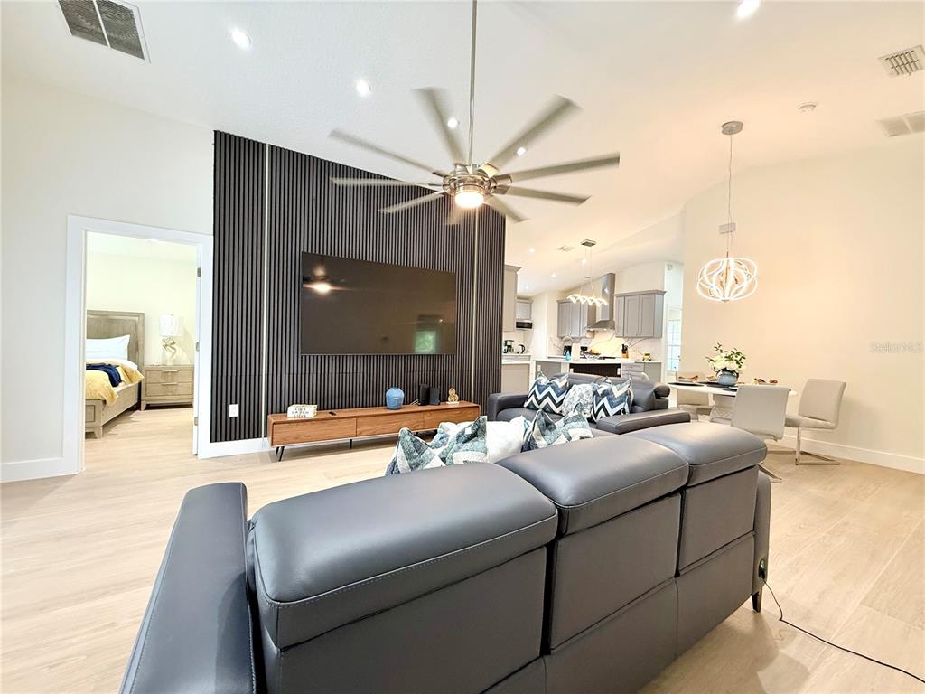 A modern living room features a slatted accent wall, a large television, and a ceiling fan — 403 SANDY RIDGE DRIVE, DAVENPORT, FL