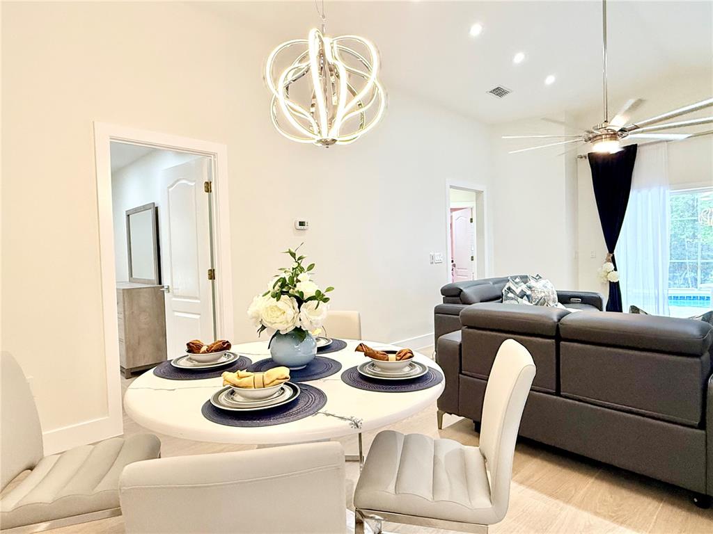 A dining area with a round table and modern chandelier sits adjacent to a living room — 403 SANDY RIDGE DRIVE, DAVENPORT, FL