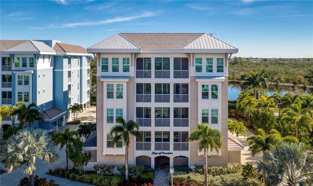 An exterior view of a multi-story residential building with screened balconies and palm trees — 395 ARUBA CIRCLE UNIT 203, BRADENTON, FL