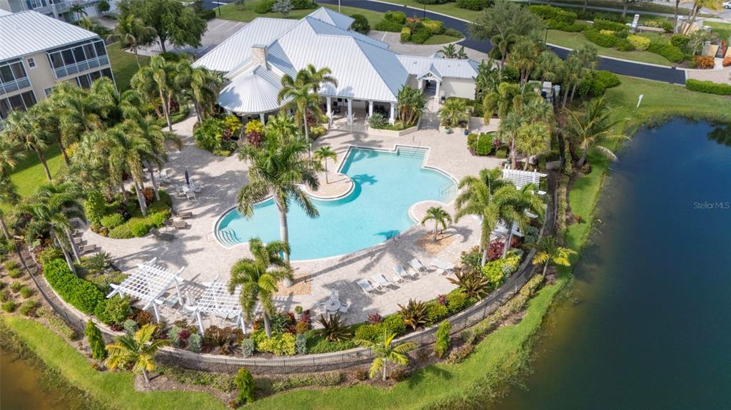 An aerial view shows a swimming pool with a deck, palm trees, and a clubhouse — 10307 CORAL LANDINGS LANE UNIT 11, PLACIDA, FL