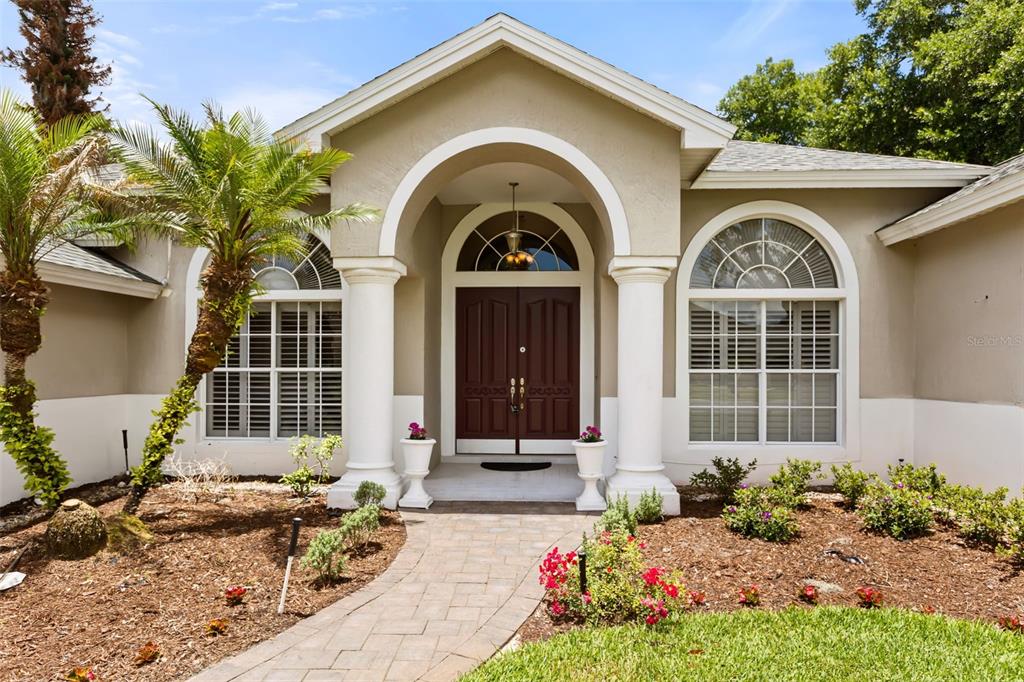 The front exterior of a house features a stone walkway leading to a double-door entrance — 1521 EDGEWATER DRIVE, MOUNT DORA, FL