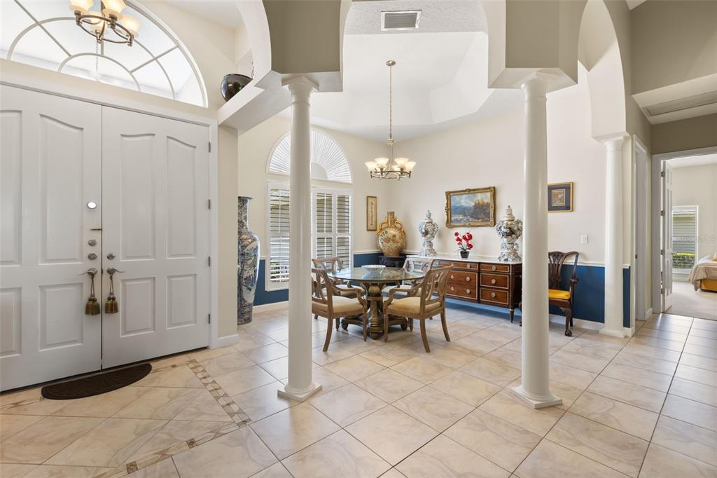A bright foyer with white columns leads into a dining area featuring tile floors — 1521 EDGEWATER DRIVE, MOUNT DORA, FL