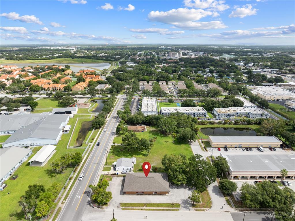An aerial view shows a commercial building with a parking lot next to a road — 323 W CYPRESS STREET, KISSIMMEE, FL