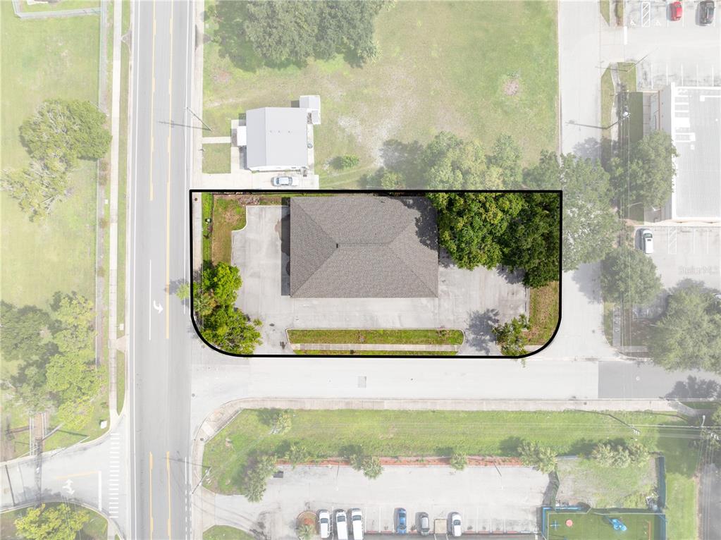 This aerial view shows a commercial building with a parking lot and surrounding landscaping — 323 W CYPRESS STREET, KISSIMMEE, FL