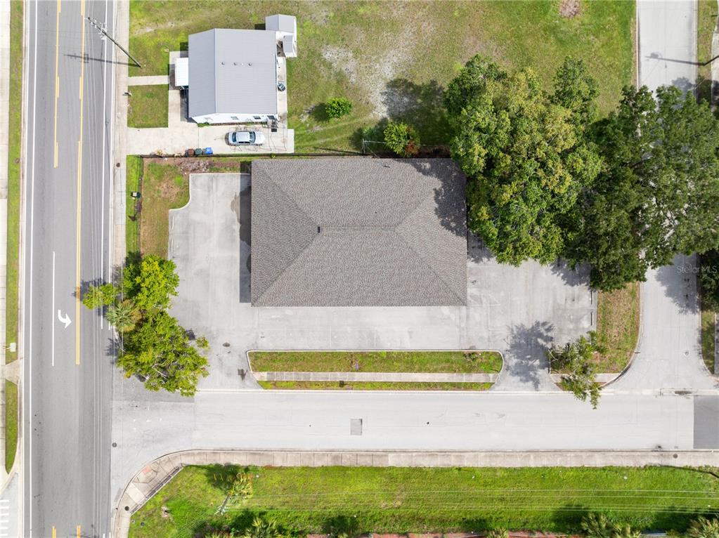 An aerial view shows a commercial building with a parking lot and surrounding landscaping — 323 W CYPRESS STREET, KISSIMMEE, FL