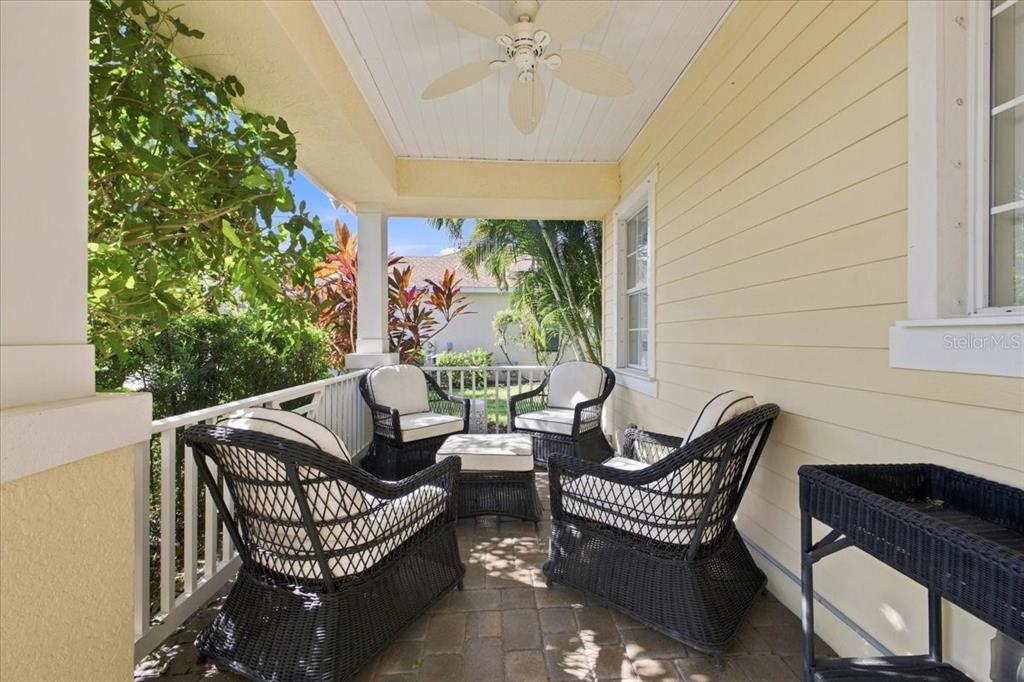 A covered porch with wicker furniture, a ceiling fan, and light yellow siding — 4704 SENECA PARK TRAIL, BRADENTON, FL