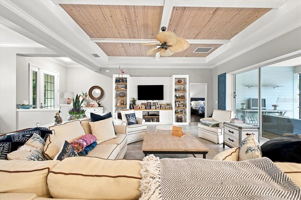 A living room features a coffered wood-paneled ceiling, a built-in media center, and neutral furniture — 4704 SENECA PARK TRAIL, BRADENTON, FL