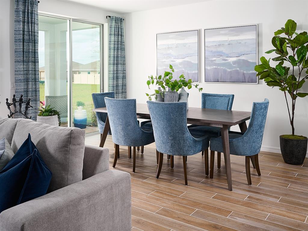 A dining area features a dark wood table, blue upholstered chairs, and a sliding glass door — 2202 SAGELAND WAY, BARTOW, FL