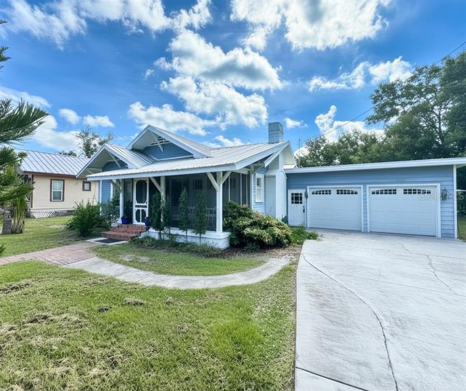 A blue single-story house with a metal roof, front porch, and attached two-car garage — 1102 N ARCADIA AVENUE, ARCADIA, FL