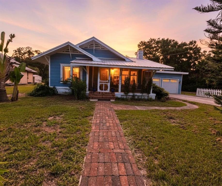 A blue bungalow with a brick walkway and a front porch at sunset — 1102 N ARCADIA AVENUE, ARCADIA, FL