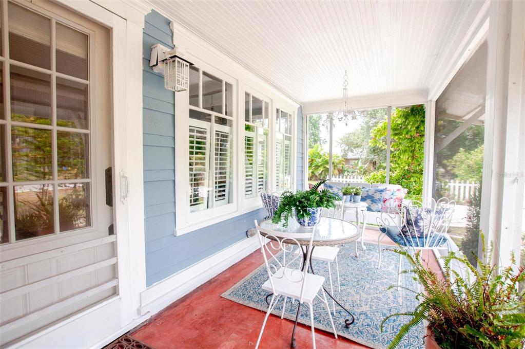 A screened-in porch features blue siding, a red concrete floor, and white patio furniture — 1102 N ARCADIA AVENUE, ARCADIA, FL