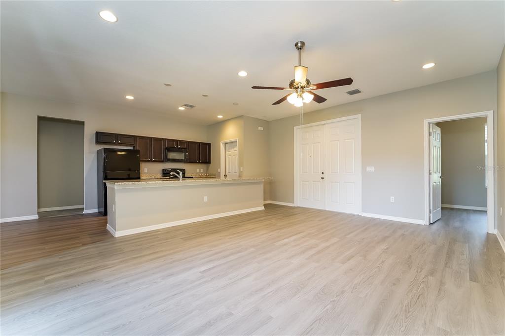An open-concept living area features light wood-look flooring, a ceiling fan, and a kitchen island — 4311 ABCOR ROAD, NORTH PORT, FL