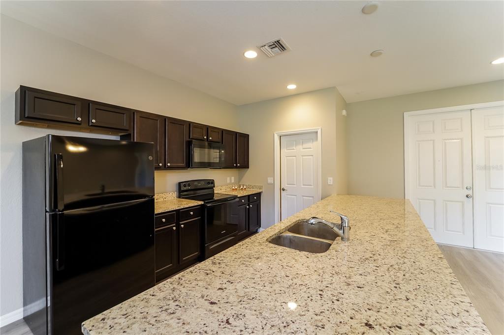 A kitchen features dark wood cabinets, granite countertops, black appliances, and a large center island — 4311 ABCOR ROAD, NORTH PORT, FL