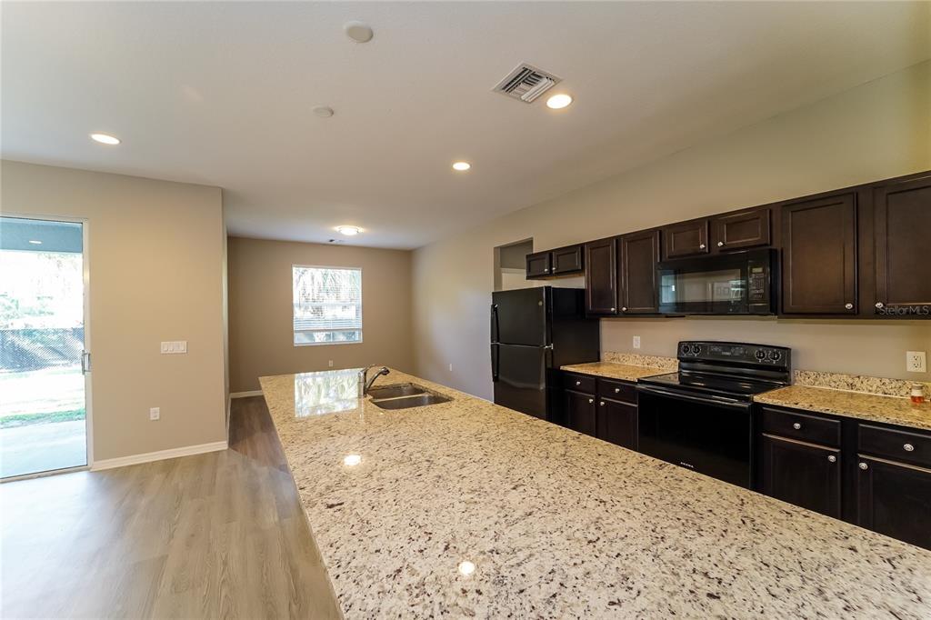 A kitchen features dark wood cabinets, granite countertops, black appliances, and a large center island — 4311 ABCOR ROAD, NORTH PORT, FL