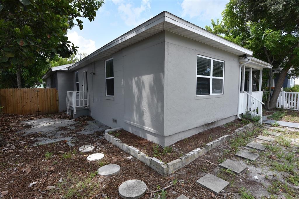 The exterior of a gray, single-story house features a small porch and concrete stepping stones — 4642 10TH AVENUE S, ST PETERSBURG, FL