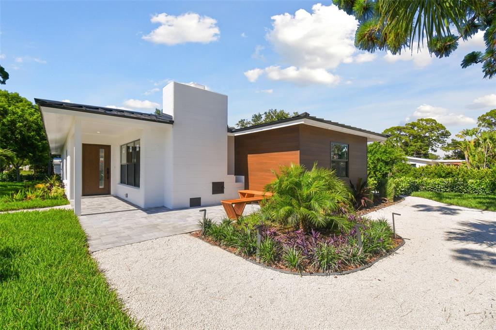 A modern house exterior features a white chimney, wood siding, and a gravel driveway — 301 AURORA STREET E, VENICE, FL