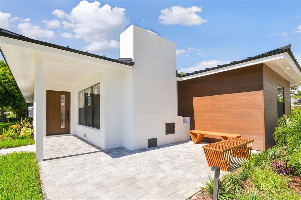 A modern house exterior features a white chimney, a paved patio, and wood-paneled siding — 301 AURORA STREET E, VENICE, FL