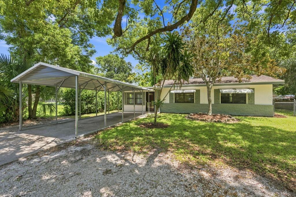 A single-story house with a metal carport and a green and white exterior — 7810 CHAPEL AVENUE, PORT RICHEY, FL