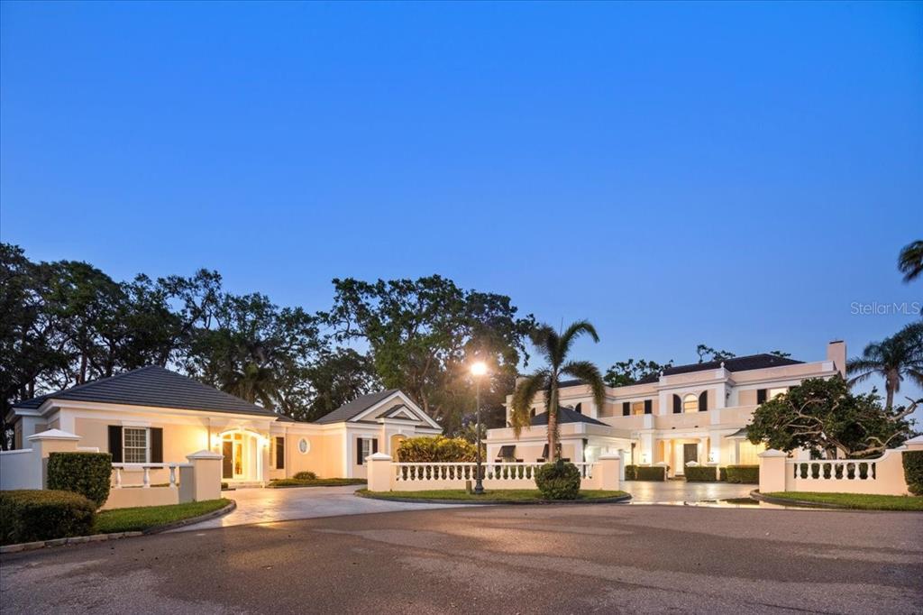 A large, multi-building estate with a paved driveway, manicured landscaping, and a clear blue sky — 236 SAINT JAMES PARK, OSPREY, FL