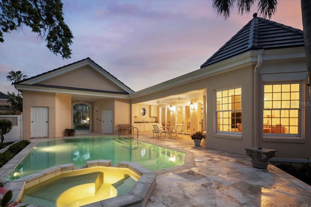 A swimming pool and hot tub sit on a stone patio beside a house exterior — 236 SAINT JAMES PARK, OSPREY, FL