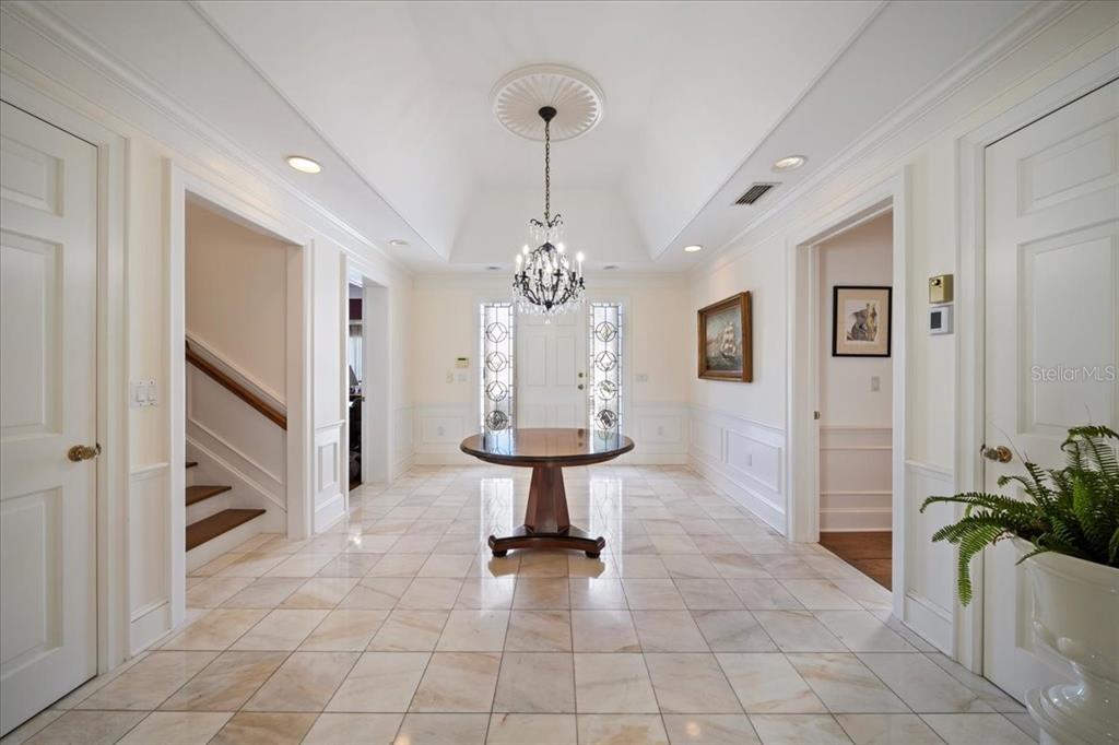 A bright foyer features a vaulted ceiling, a crystal chandelier, marble flooring, and a round table — 236 SAINT JAMES PARK, OSPREY, FL