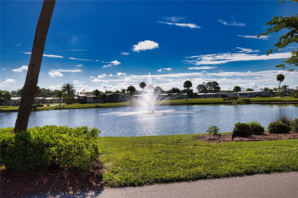 A water fountain sprays in the center of a pond surrounded by houses and palm trees — 670 ALVARADO, NORTH PORT, FL