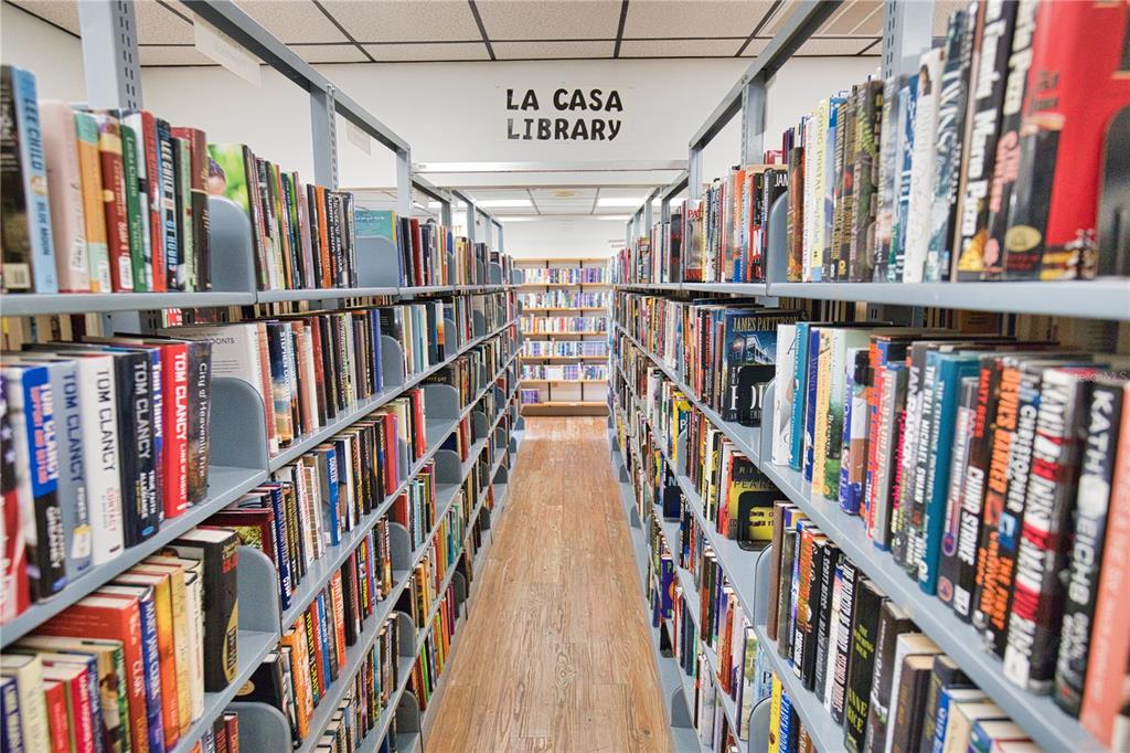 A narrow library aisle features metal bookshelves filled with books on both sides — 670 ALVARADO, NORTH PORT, FL