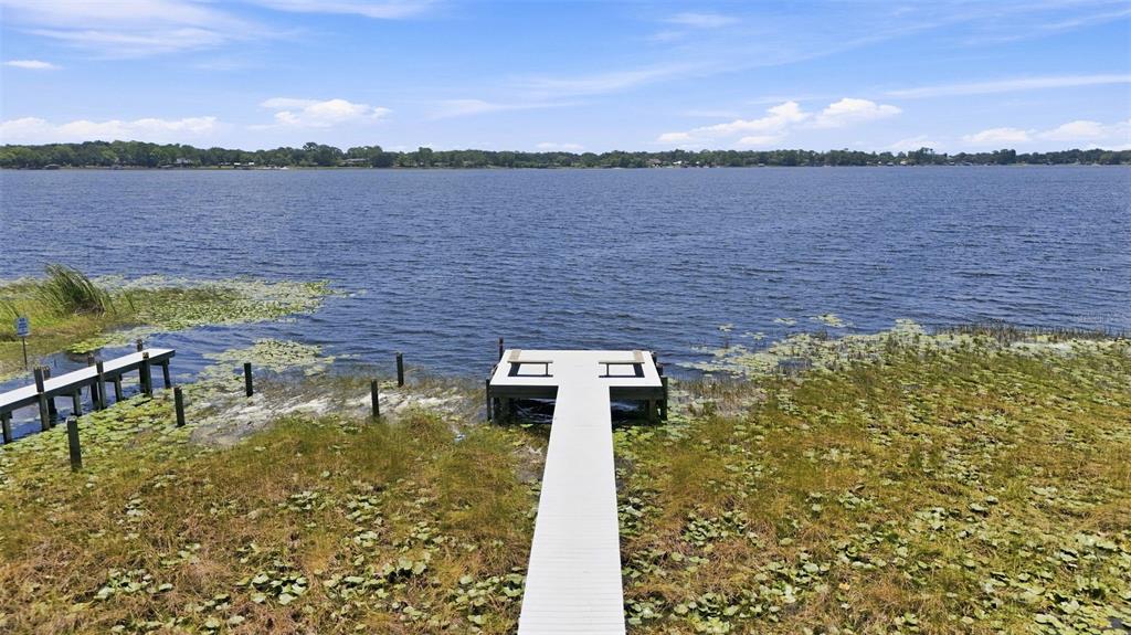 A wooden dock extends into a lake surrounded by marshy vegetation under a blue sky — 3104 GARDEN ROAD, EUSTIS, FL
