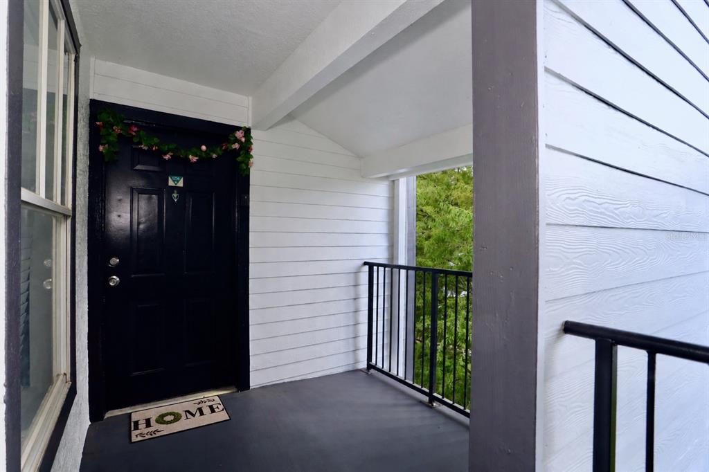 An exterior view of a covered apartment entryway with a black door and balcony railing — 2217 GRAND CAYMAN COURT UNIT 1236, KISSIMMEE, FL