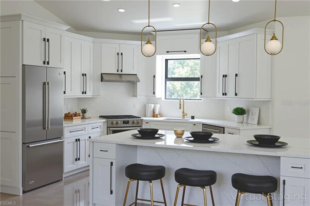 A modern kitchen features white cabinetry, stainless steel appliances, a quartz island, and gold lighting — 1506 8TH AVENUE, LEHIGH ACRES, FL
