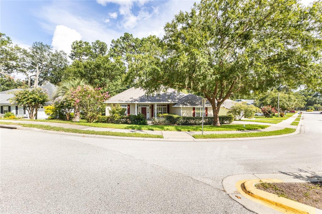 A single-story house with beige siding sits on a corner lot with mature trees — 2429 NW 93RD STREET, GAINESVILLE, FL