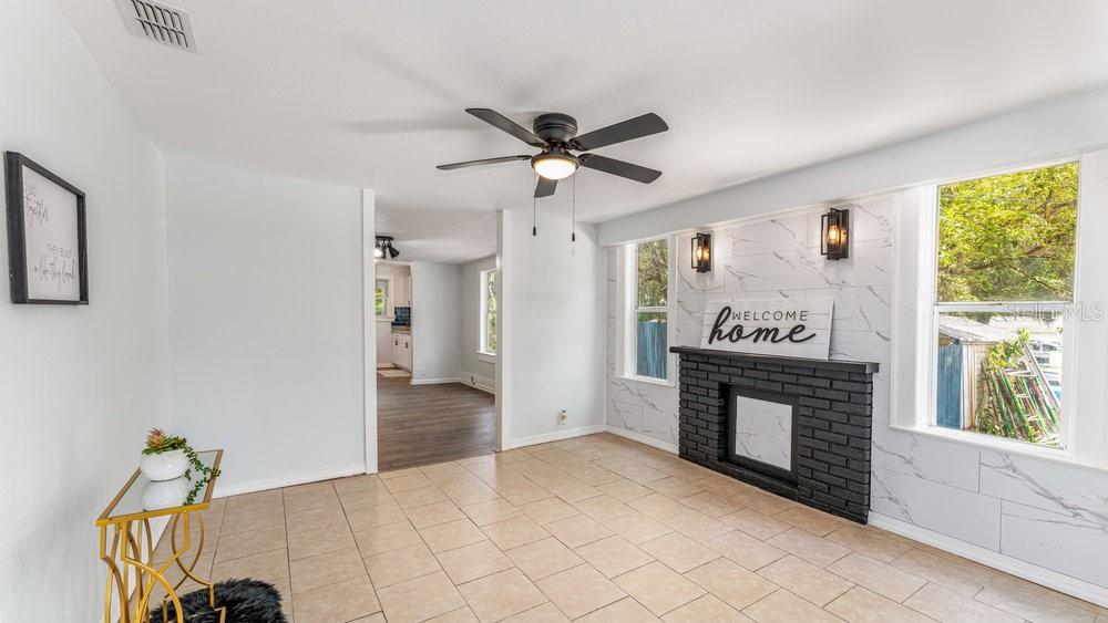 A living room features tile flooring, a black brick fireplace, and white marble-look wall panels — 912 E CAROLINA AVE, DELAND, FL
