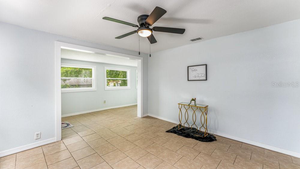 A room with light blue walls, tan tile flooring, a ceiling fan, and a console table — 912 E CAROLINA AVE, DELAND, FL