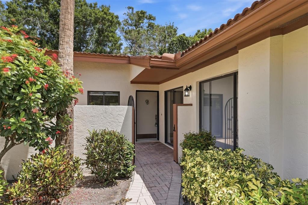 A paved walkway leads to the front entrance of a house with a tiled roof — 6403 PELICAN DRIVE, BRADENTON, FL