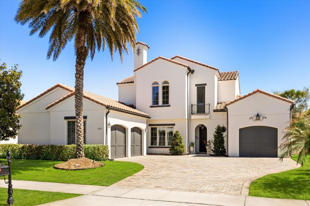 A two-story stucco house with a tile roof, arched garage doors, and a palm tree — 12411 MONTALCINO CIRCLE, WINDERMERE, FL