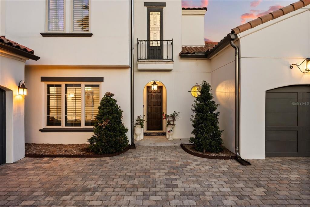 The exterior of a two-story stucco home features a paved driveway, arched entryway, and balcony — 12411 MONTALCINO CIRCLE, WINDERMERE, FL