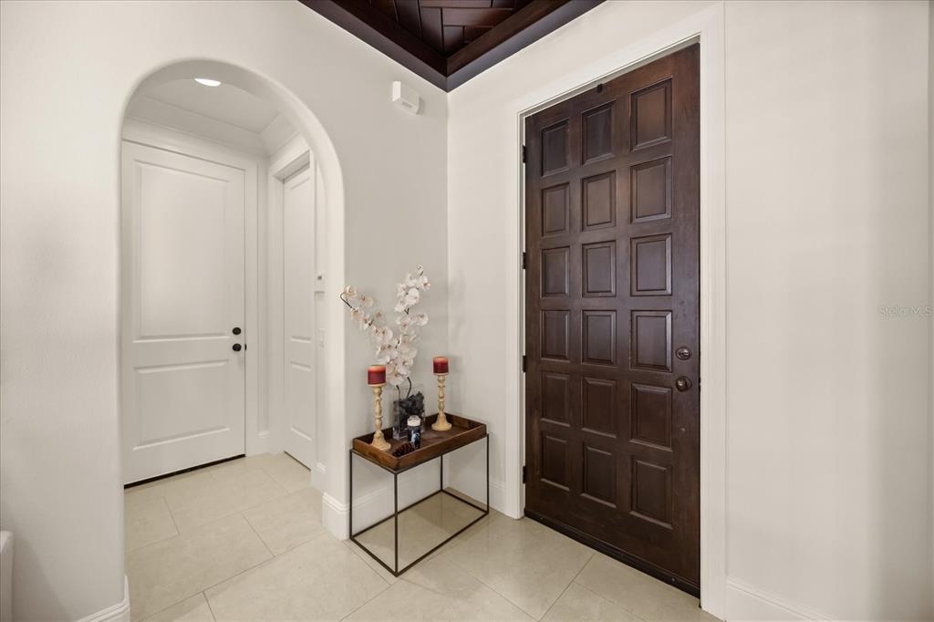 A foyer features a dark wood paneled door, an arched doorway, and a console table — 12411 MONTALCINO CIRCLE, WINDERMERE, FL