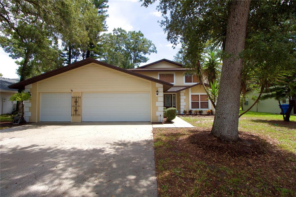 A two-story house with a two-car garage, light yellow siding, and a concrete driveway — 1817 LAURENCE COURT, CLEARWATER, FL