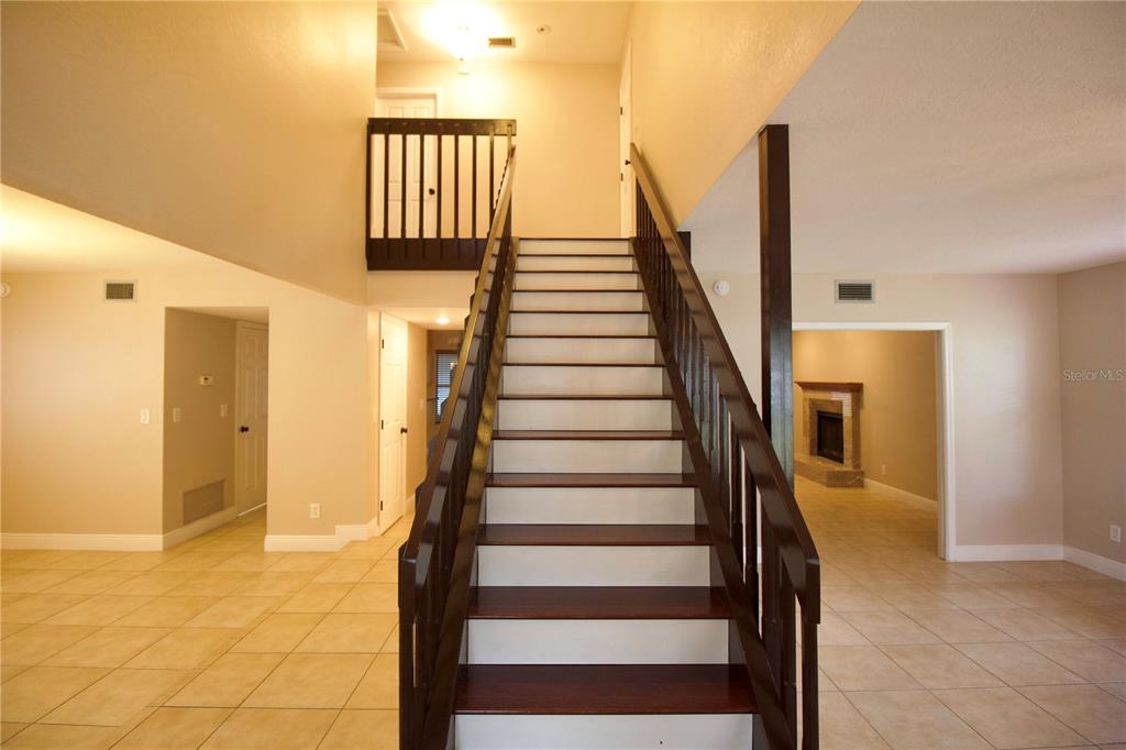 A central staircase with dark wood treads and railings sits in a tiled foyer — 1817 LAURENCE COURT, CLEARWATER, FL