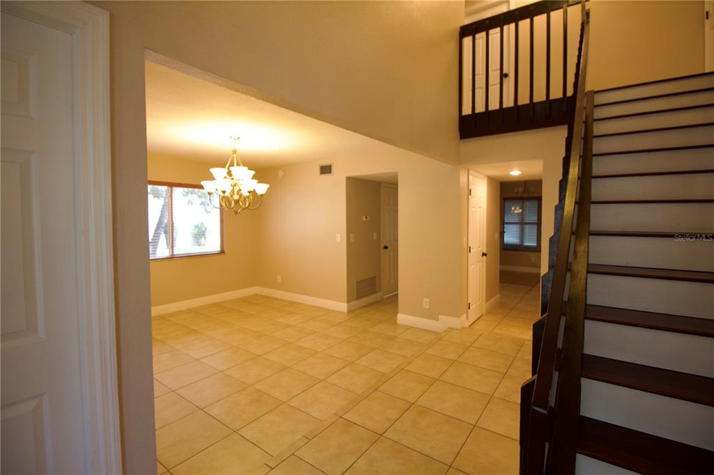 An interior view showing a tiled dining area, a staircase, and a lofted landing — 1817 LAURENCE COURT, CLEARWATER, FL