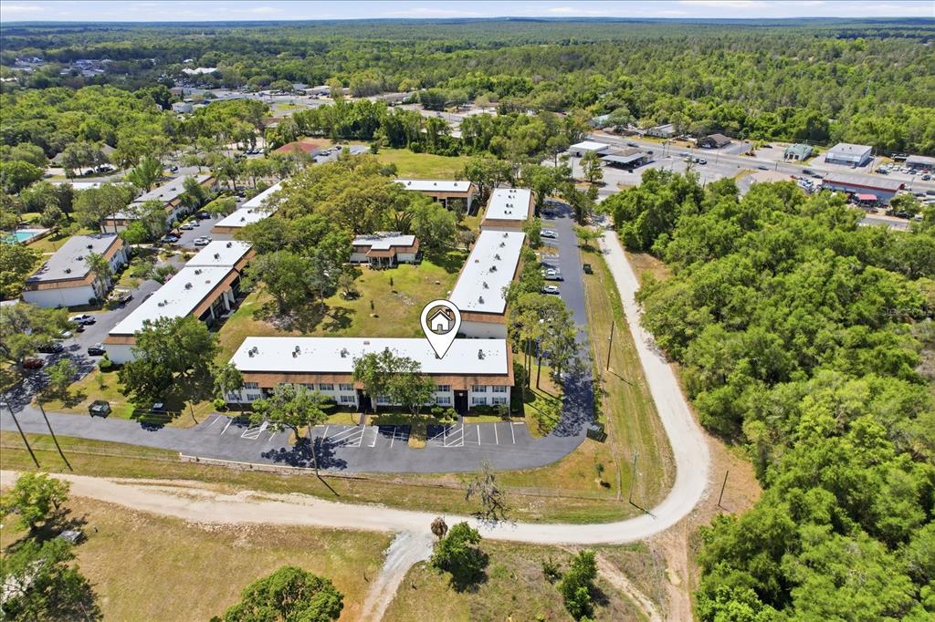 An aerial view shows a multi-building apartment complex surrounded by trees and parking lots — 2400 FOREST DRIVE UNIT 149, INVERNESS, FL