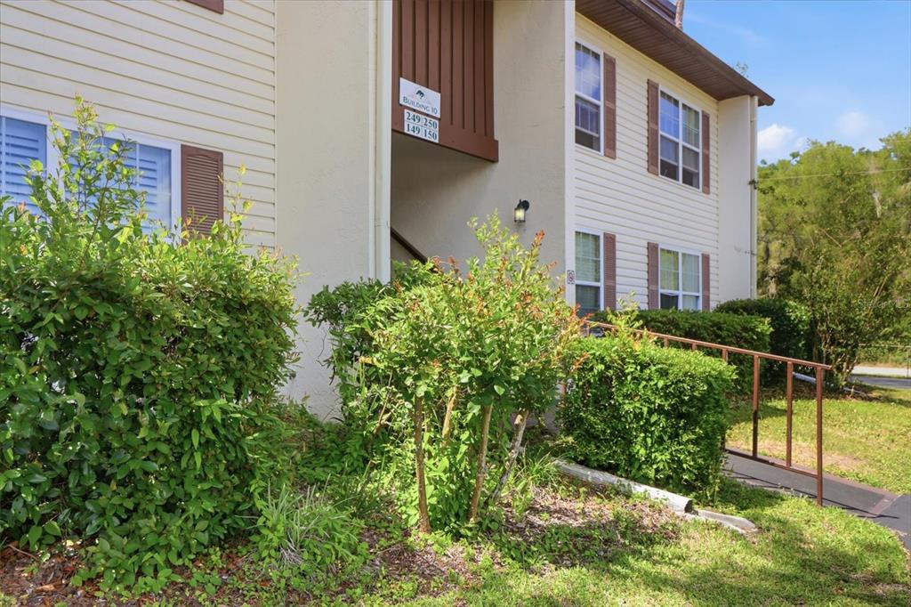 Exterior view of a two-story apartment building with beige siding and a metal ramp — 2400 FOREST DRIVE UNIT 149, INVERNESS, FL
