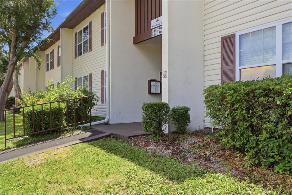 The exterior of a two-story apartment building features beige siding, brown shutters, and a walkway — 2400 FOREST DRIVE UNIT 149, INVERNESS, FL